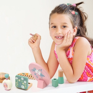 Girl playing with premium pink wooden makeup toy set featuring floral patterns