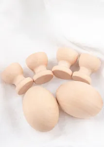 Detailed close-up of smooth unpainted wooden eggs and holders on white linen fabric