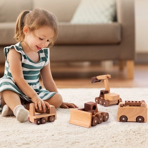 Set of four wooden construction vehicle toys for children on a soft white rug