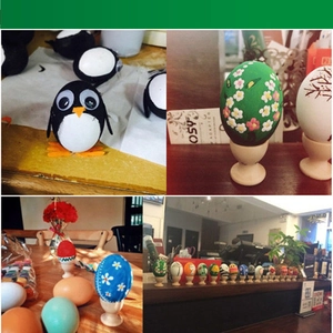 Detail of hand-painted wooden eggs with penguin and floral motifs on tiny stands