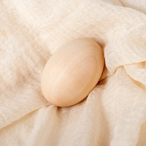 Realistic wooden toy egg with natural wood grain for DIY painting on beige linen cloth