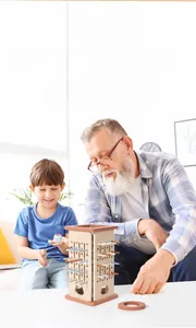 Toddler playing a wooden stick balance game with a grandfather for color cognitive learning