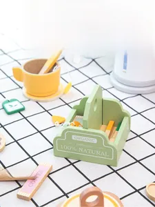 Detail of wooden tea set toys including organic box, coffee cup, and stirrers on tablecloth
