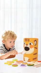 Close-up of a child using a spoon to feed wooden food pieces to a tiger toy bucket