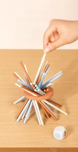 Action shot of wooden balance game showing hand pulling a stick from the wooden ring