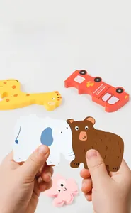 Close-up of a child's hand gripping large animal puzzles including a red fire truck