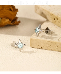 Macro shot of S925 sterling silver four-point star earrings with light blue gemstone