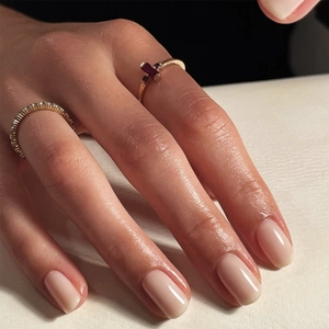 Close-up of gold ring set with red rectangular gemstones and diamond band on hand