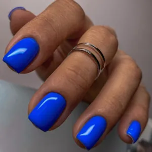 Detail of medium square Klein blue press-on nails with silver ring accessories
