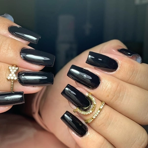 Macro detail of glossy black long square press-on nails with decorative gold rings