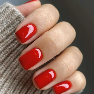 Close-up of glossy bright red medium-square press-on nails with autumn knit sweater