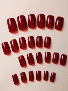 Close-up of 24pcs glossy dark red press-on nails in various sizes on a plain background