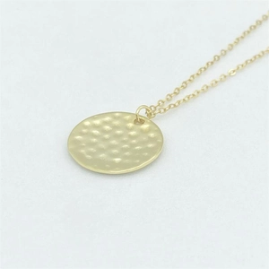 Macro shot of s925 sterling silver hammered texture pendant with fine gold link chain