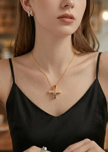 Gros plan d'un collier croix plaqué or avec zircons colorés porté par un mannequin