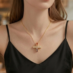 Collier croix en or avec cristaux de zircon colorés sur un modèle en robe de soie noire