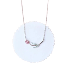 Elegant silver tulip pendant necklace with pink bloom and green leaves on a white tray