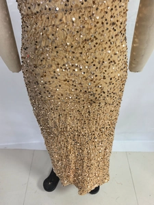Close-up of champagne gold sequined dress with vertical pleats and reflective finish