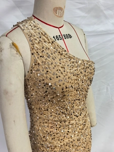 Detail of ruched champagne gold sequins on an asymmetric one-shoulder evening party dress