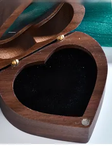 Macro shot of 3EX cut silver ring with three round stones in a heart wood jewelry box