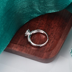 Eleganter S925 Sterlingsilber Moissanit Ring mit Sechs-Klauen-Fassung auf rotem Holzgrund