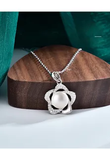 Gros plan du pendentif fleur en argent avec perle d'eau douce sur support en bois
