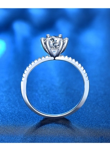 Gros plan d'une bague en argent à six griffes avec moissanite brillante et pierres de côté