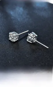 Macro view of classic four-prong moissanite stud earrings in polished 925 silver