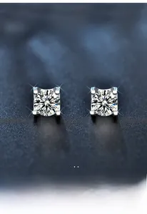 Close-up of S925 sterling silver four-prong moissanite earrings on blue texture