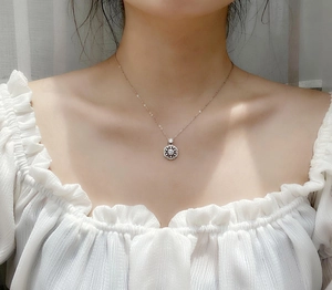 Detail of a 925 sterling silver cherry blossom pendant necklace with moissanite on a model