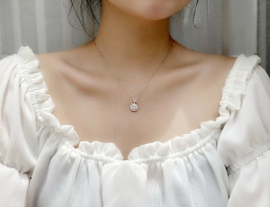 Macro shot of 925 sterling silver four-leaf clover necklace on model with white blouse