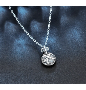 Detail of 925 silver clover necklace with hollow spherical pendant and sparkling crystal