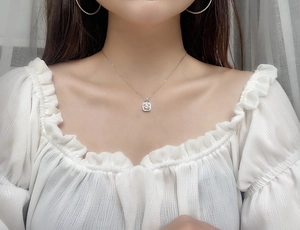 Gros plan du pendentif flacon de parfum en argent avec des diamants moissanites carrés