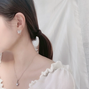 Detail view of 925 silver bow earrings and necklace set worn by a female model