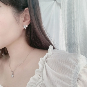 Close-up of elegant silver bow earrings with sparkling diamonds on female model