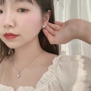 Detail shot of dainty silver bow earrings and matching solitaire necklace on a model