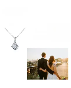 Macro view of pear-cut moissanite pendant with small side diamonds on a silver chain