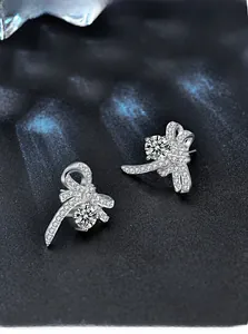 Macro view of silver bow stud earrings with sparkling moissanite and micro-pave stones