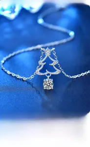 Macro shot of 925 silver Christmas tree pendant with round moissanite on blue background