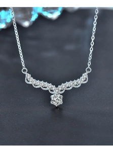 Detail of V-shaped silver necklace with moissanite pendant on a dark background