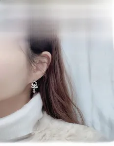 Close-up of sterling silver Christmas bell earring with moissanite and bow on ear