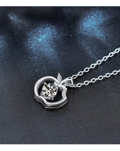 Macro shot of silver apple pendant with moissanite stone and fine pavé details
