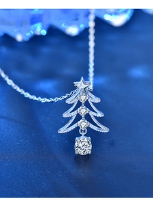 Makroansicht des Weihnachtsbaum-Anhängers mit Moissanit-Steinen auf blauem Bokeh-Grund