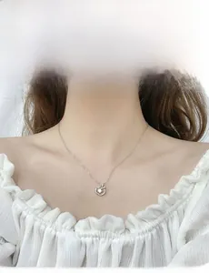 Close-up of 925 sterling silver apple pendant necklace with moissanite on model's neck