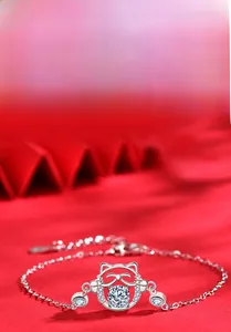 Macro shot of 925 sterling silver lucky cat bracelet with moissanite on red background