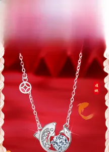 Close-up of 925 sterling silver koi fish necklace with clear zircon on red silk background