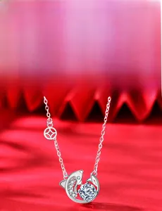 Detail of 925 silver koi pendant with moissanite stone and coin charm on red silk