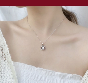 Macro detail of silver cat-ear circle pendant with moissanite on a delicate chain