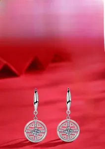 Détail macro de boucles d'oreilles pièces en argent 925 avec Moissanite sur fond rouge