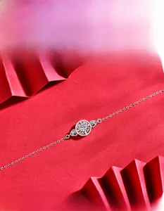 Detail of silver chain bracelet with hollow coin motif and sparkling center zircon