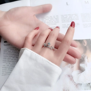 Macro detail of silver crown-shaped ring with moissanite sparkle on model hand